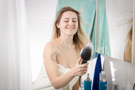 妇女用浴巾遮盖的肖像擦干头发图片