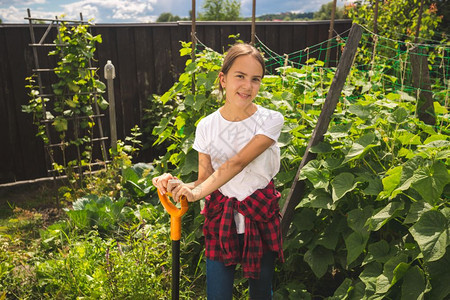 穿着惠灵顿靴子的年轻女孩拿着铲子在花园工作图片