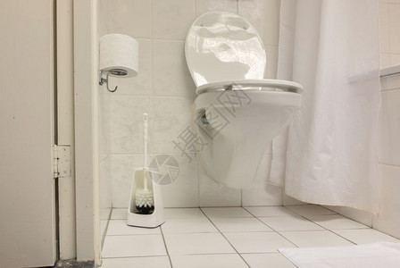 在一个简单的洗手间白色瓷砖中的厕所刷子图片