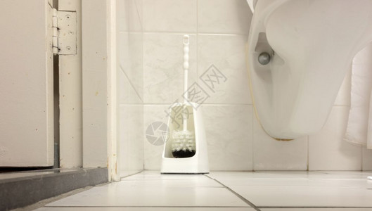 在一个简单的洗手间白色瓷砖中的厕所刷子图片