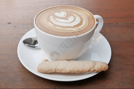 咖啡拿铁心型在一个白色杯子和饼干木制背景图片
