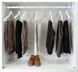 棕色皮鞋和一排黑裤子挂在衣柜里图片