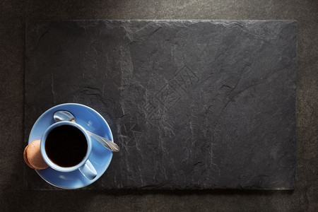 纯黑色石板背景的蓝色茶杯图片
