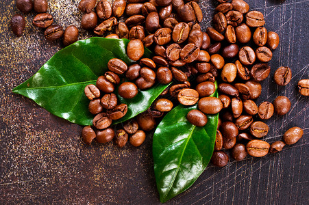 咖啡豆和咖啡桌上的咖啡豆和绿叶背景