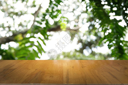 在户外花园灯光的抽象模糊背景前的黑木桌图像可以用于显示或装配您的产品图片