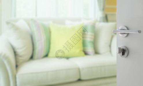 在现代沙发上用绿色枕头打开通往客厅的白色门图片