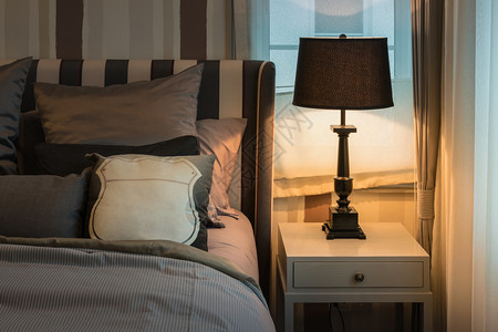 室内舒适的卧有深棕色枕头和床边桌上的阅读灯背景图片