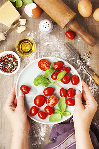 女在生锈背景下烹饪意大利食品Parmigiano番茄Basil橄榄油的手图片