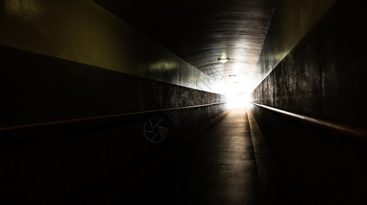 地下一条长的斜坡道隧尽头有白天背景图片