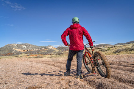 一个疲累的男骑自行车的男手准备在科罗拉多红山露天大洞洗手道的深沙砾上经历艰难而漫长的旅程背景图片