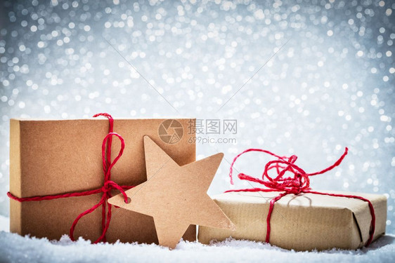 重新生化的圣诞礼物以闪光背景在雪中的礼物手工制作的生态纸包装重新生化的圣诞礼物以闪光背景在雪中的礼物图片
