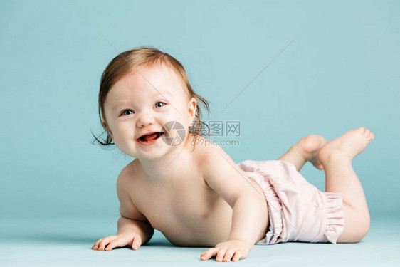 快乐的小孩在蓝背景的地上爬可爱婴儿快乐小孩在地上爬图片
