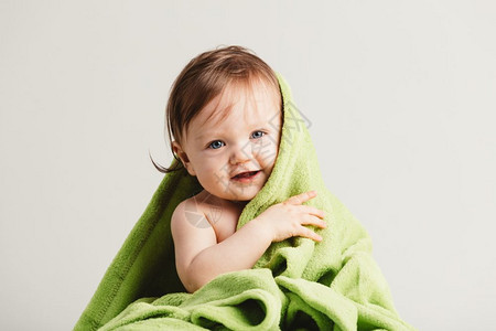 可爱的小宝从舒适绿毯子里爬出来幼稚的照顾和天真图片