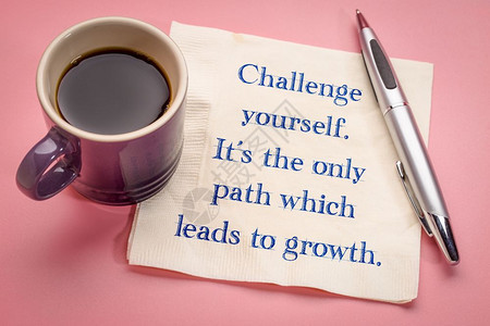 挑战你自己这是通往成长的唯一道路在餐巾纸上写有灵感的笔迹加上一杯咖啡背景图片