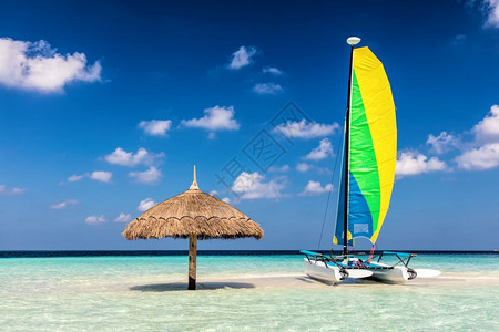热带沙滩岛加遮阳伞的Catamaran印度洋马尔代夫蓝晴天印度洋图片