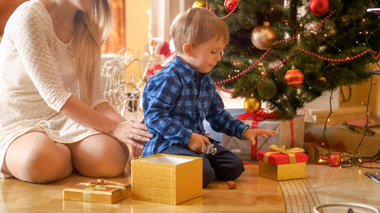 托德勒男孩上午在客厅打开圣诞礼物盒可爱的幼儿男孩在客厅打开圣诞礼物盒图片