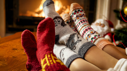 家庭穿着温暖的羊毛袜子在房的壁炉边升温图片