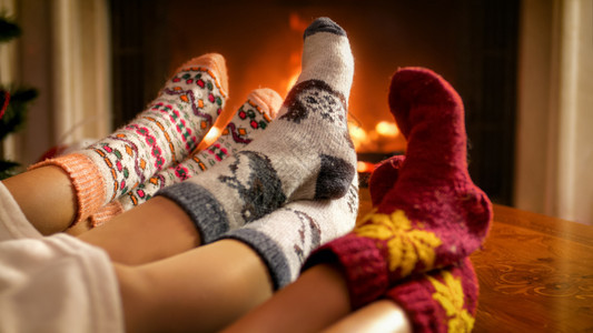 在客厅燃烧的壁炉旁边暖编袜子中家庭脚的贴近照片在客厅燃烧的壁炉旁边温暖编织袜子上家庭脚的贴近图像图片