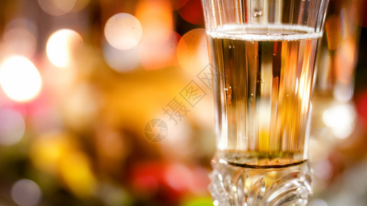 香槟的紧贴照片香槟的装满玻璃杯子与闪亮多彩的圣诞灯相对香槟的装满玻璃图片图片