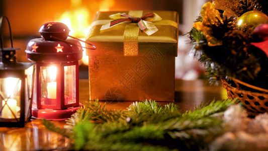 灯笼和黄金礼物盒中的蜡烛与圣诞花圈对比灯笼和黄金礼物盒中蜡烛与圣诞花圈对比的近灯照片图片