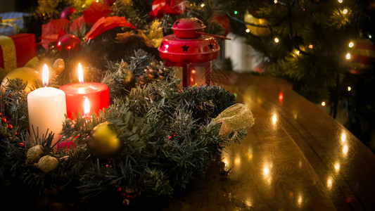 木板上装饰花环灯笼和燃烧蜡烛的紧贴照片以对抗亮圣诞灯光木板上装饰花环灯笼和燃烧蜡烛的紧贴图像以对抗照亮圣诞灯光图片