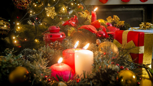 三根蜡烛对着闪亮的圣诞灯图片