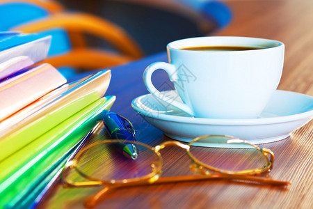 创意抽象商业办公用物和司静止生活概念从宏观角度看白色瓷茶咖啡杯或子加热饮料眼镜彩色档案夹和蓝球笔放在木制办公桌上有选择焦点效果图片