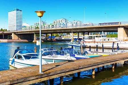 芬兰赫尔辛基Hakaniemi区装有桥梁建筑和对接机动船只的码头夏季风景图片