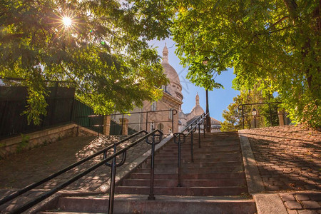 典型的阳光明媚蒙马特楼梯清晨到圣心教堂的楼梯阳光穿过树林巴黎蒙马特广场巴黎法国蒙马特楼梯图片