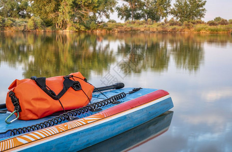 在科罗拉多北部的平静湖岸上夏季风景中用桨安全皮带和防水护身衣站起桨板在夏季风景中划桨安全带和防水护身衣图片
