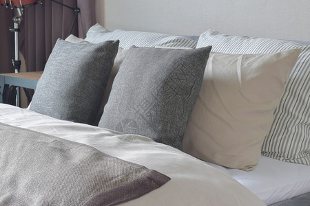 深灰色和白枕头用舒适的毯子铺在床上图片