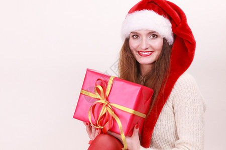 穿着圣达克萨斯帽子的漂亮女人拿着红色大礼物盒带丝圣诞幸福冬天和人的概念图片