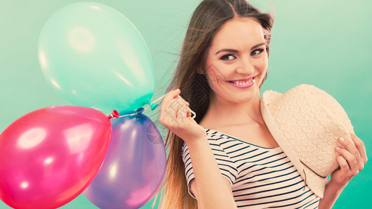 快乐和夏天年轻有魅力的快乐女人戴着草帽满身多彩的气球绿色背景玩彩气球的快乐女孩图片