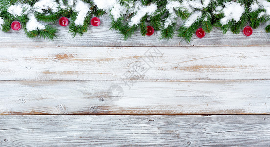 雪的顶端边界覆盖了圣诞常青树枝和白旧木上的红蜡烛图片