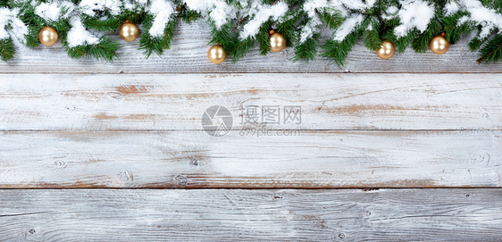 雪的顶端边界覆盖了圣诞常青树枝和白旧木的金饰品图片