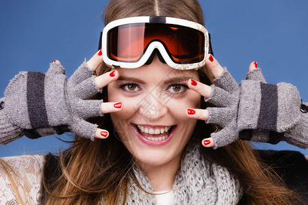 穿着温暖衣服的滑雪女郎身着谷歌画像的女郎冬季体育活动在蓝工作室拍摄的镜头上展示手套和红指甲的漂亮女运动员身着温暖衣服的滑雪谷歌画图片