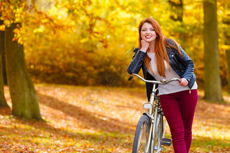 骑自行车女郎在秋天公园散步图片