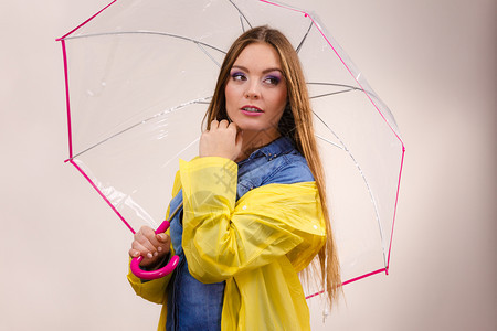 身着防水的黄大衣有透明伞式保护的女时装雨衣少气象学预报和天气季节概念身着防水大衣的妇女则身着雨伞式保护图片