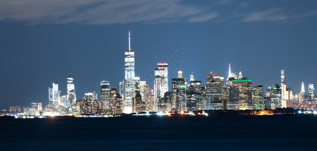 建筑物在夜间照亮穿过上海湾和哈德逊河望向曼哈顿区图片