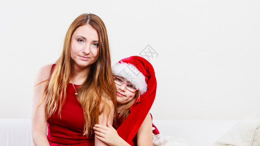 母亲穿着圣诞礼服女孩戴圣达克拉斯帽图片