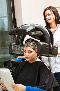 头发放松和型概念坐在黑披风上的女人在机器下脱发图片