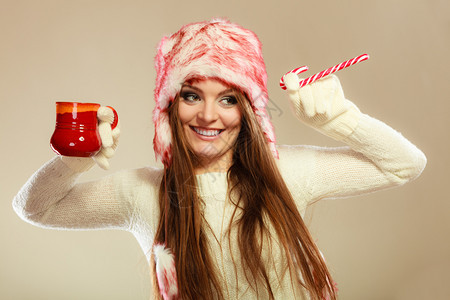 女孩拿着羊毛白手套玩得开心圣诞节时间概念女孩玩手杖和杯子图片