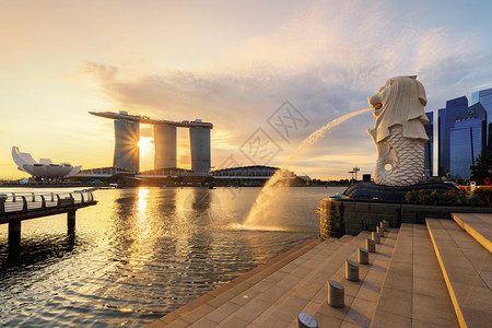 城市日落日出时Merlion和MarinaBay沙与新加坡市中心和金融区摩天大楼背景