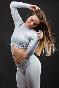 运动健身服装概念热有吸引力的女士穿热身服装的年轻诱人女孩拉着衬衫在黑色上展示热身服装穿的适合运动妇女图片