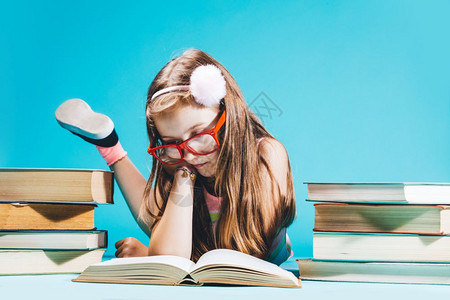 女孩坐在书旁学习蓝背景回到学校年轻生小女孩坐在书边学习图片