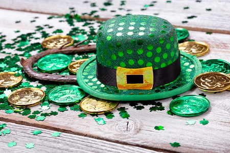 亮绿色帽子配有金硬币火石和生锈的马蹄铁用于圣帕特里克日以近身形式在白色生锈木背景上图片