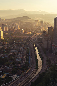 马来西亚城市吉隆坡市中心与山丘马来西亚和公路的空中景象亚洲智能城市的金融区和商业中心日落时天梯和高楼建筑背景