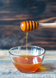 黑暗木背景上的一碗蜂蜜图片
