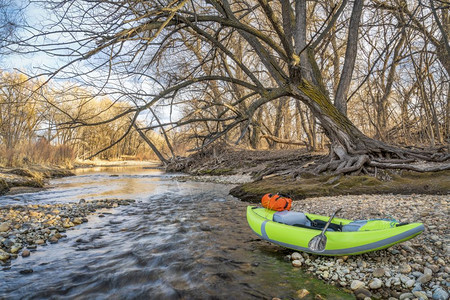 河岸上一条带桨和防水的斗篷白充气皮艇科罗拉多福特柯林斯堡的Poudre河早春风景和低水图片