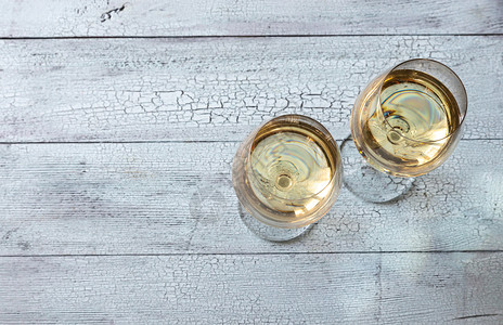 两杯白葡萄酒放在木背景上图片